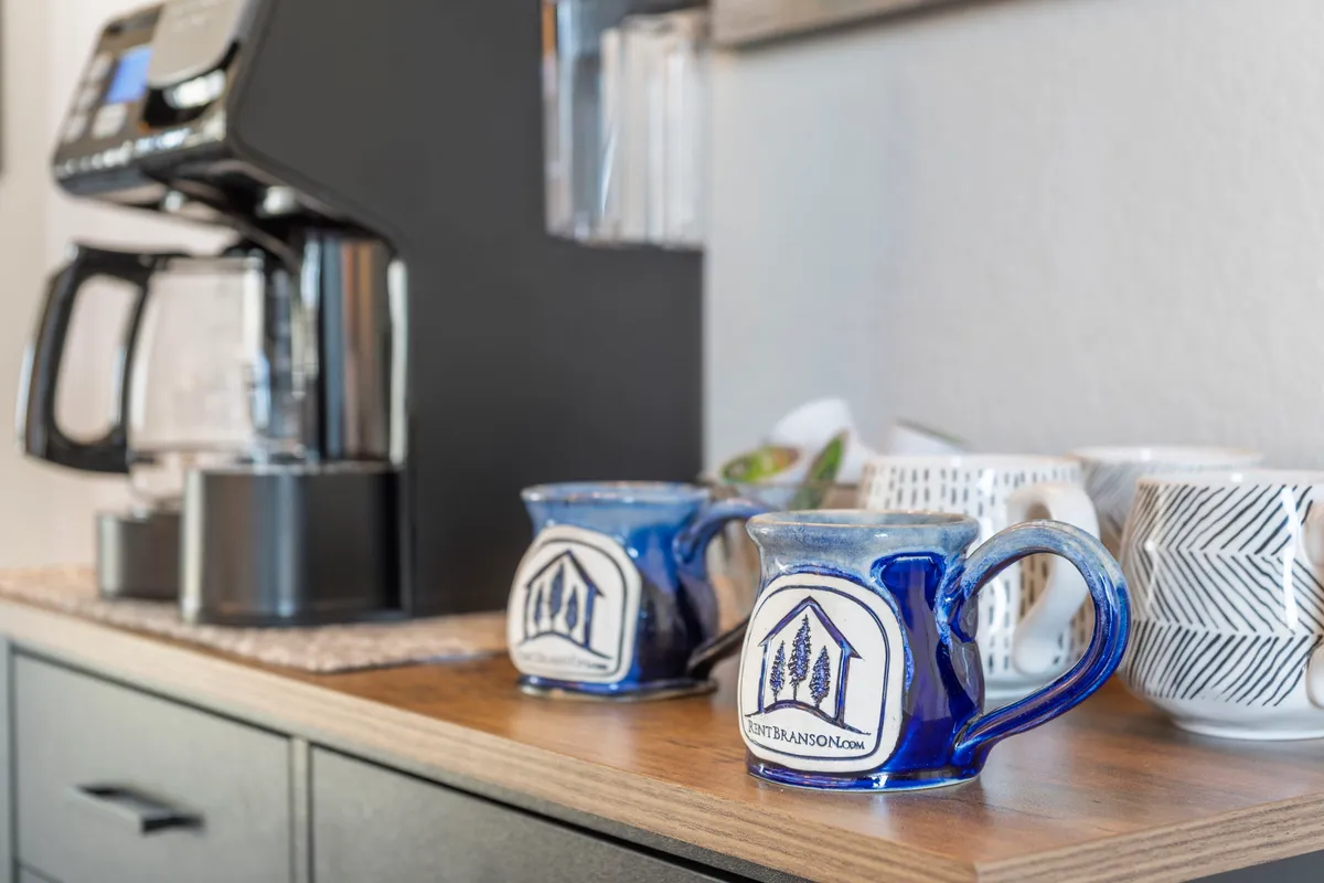 A cozy interior shot features a coffee maker placed on a wooden countertop with two blue mugs. The inviting setup suggests a morning ritual of brewing coffee, ready to be enjoyed, perhaps just steps away from the patio.